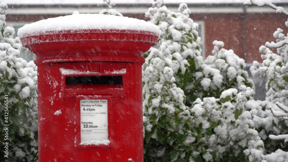 A Red post box in the falling snow at Christmas A Red post box in the falling snow at Christmas