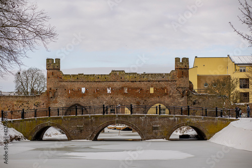 Panorama of historic city wall river portal Berkelpoort in Zutphen, The Netherlands, in winter after a snowstorm with frozen water and functional bridge in the foreground photo