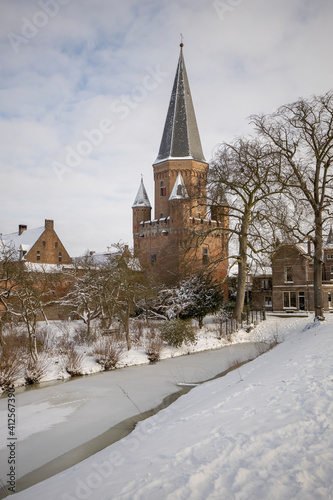 Snow white winter wonderland with pointy rooftop tower with cants of Drogenapstoren part of historic city center of medieval Hanseatic town during a snowstorm
