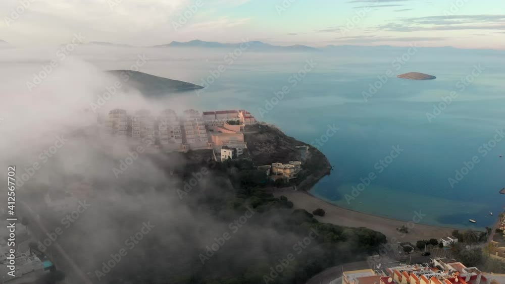 Aerial drone point of view La Manga del Mar Menor spanish touristic resort city during misty weather in early morning, residential buildings rooftops and Mediterranean Seascape. Murcia, south of Spain