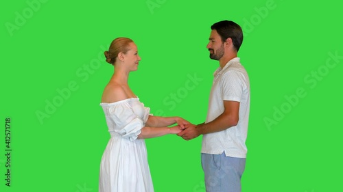 Young couple in love holding hands looking at each other on a Green Screen, Chroma Key. photo