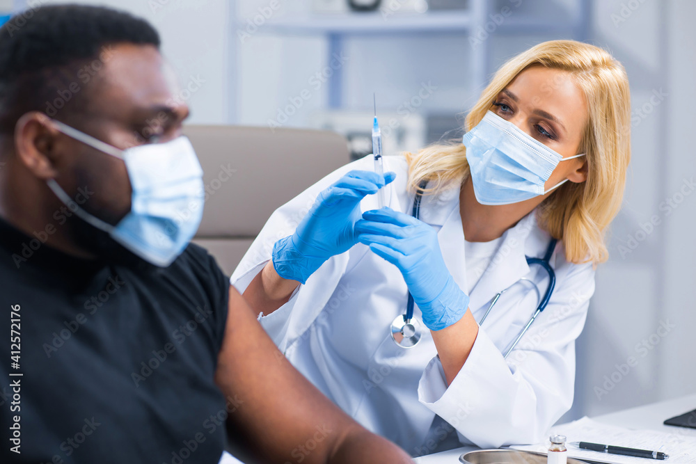 Professional doctor makes a coronavirus vaccine using a syringe and hypodermic needle. Professional medical worker and patient at the hospital office. Vaccination and safety. Professional doctor makes a coronavirus vaccine using a syringe and hypodermic needle. Professional medical worker and patient at the hospital office. Vaccination and safety.
