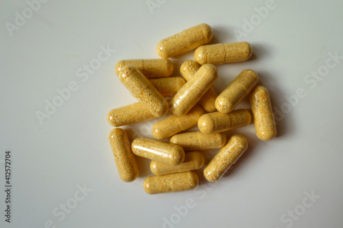 View of handful of orange cellulose capsules of multivitamins from above