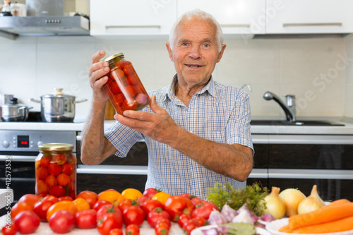 Obraz na płótnie old gray haired man makes harvests for the winter pickles tomatoes