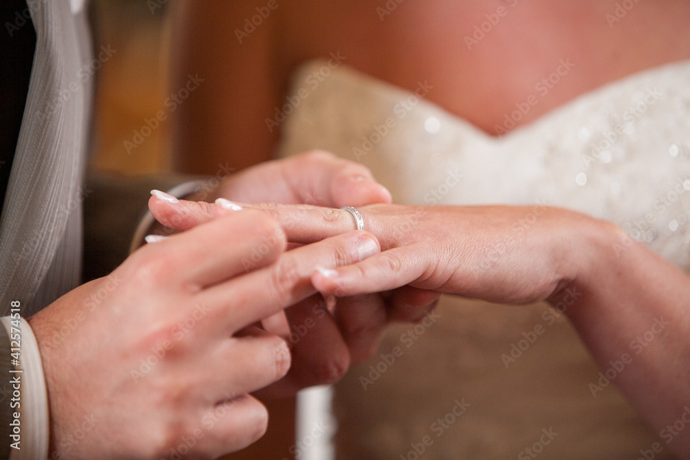 Closeup of bride putting a wedding ring onto the groom's finger. Couple exchanging wedding rings. High quality photo Closeup of bride putting a wedding ring onto the groom's finger. Couple exchanging wedding rings. High quality photo