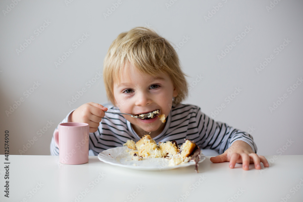 Cute toddler child, eating piece of cake and drinking juice Cute toddler child, eating piece of cake and drinking juice