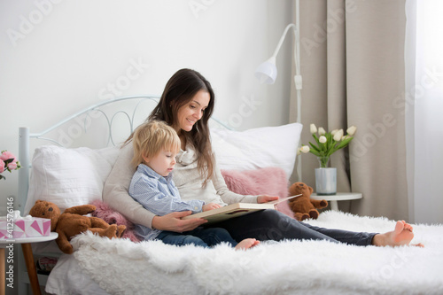 Mother and child, toddler boy, reading book in bed photo