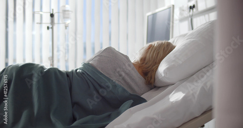 Back view of sick woman sleeping on side in hospital bed