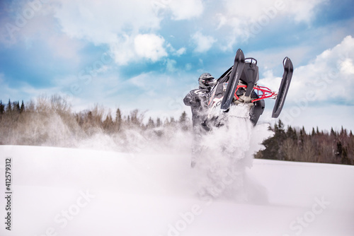 Person jumping wth a snowmobile polaris skidoo in powdery snow in quebec canada