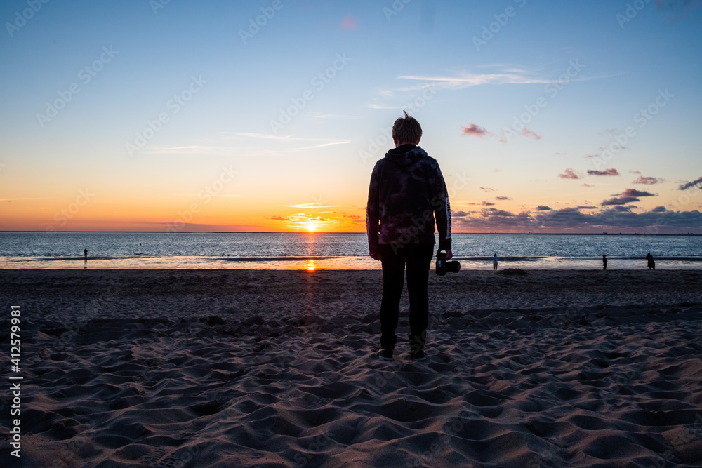Silhouette of a young man photographer taking picture on the beach ,sunset scene. High quality photo