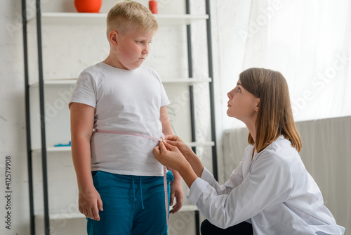 Tablou pe pânză Little chubby boy being measured by a friendly doctor