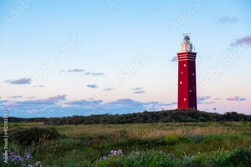 Lighthouse standing on the Dutch coast with a dramatic. and colorful dusk or dawn sky behind it. High quality photo