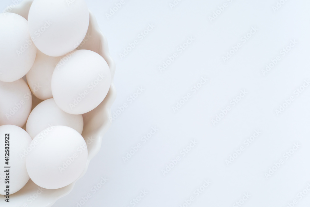 White eggs in a white dish on a light background. Copy space, top view.