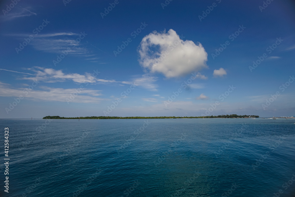 blue skies and white clouds above the island and sea