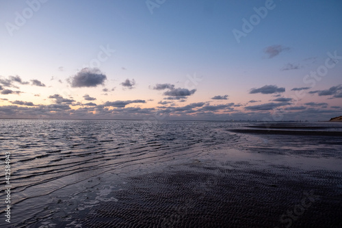 View of the setting sun shining on the Sea and reflected on the beach  clouds with sun-shining edges. Landscape. High quality photo showing concept of freedom and dreams