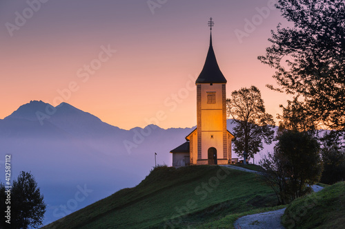 Jamnik, Slovenia, church of St. Primoz, Julian Alps at background.