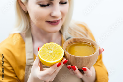 Happy young woman holding wooden bowl of honey, copy space