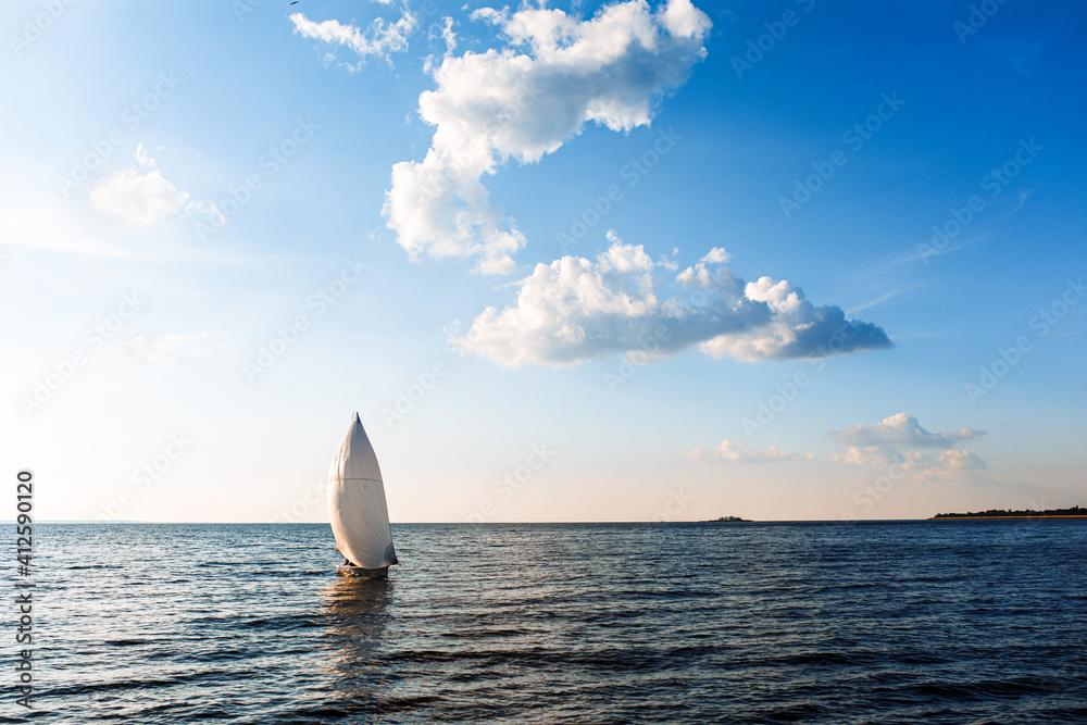 White sailing yacht in the blue ocean. White yacht with sails against the blue sky