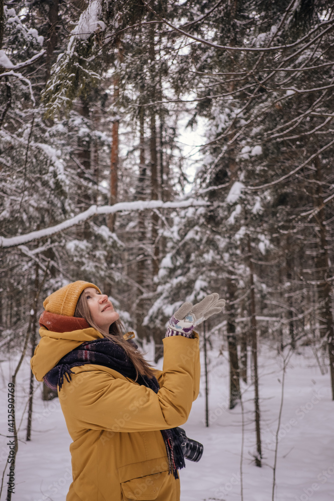 Young Cheerful woman spending time in winter snowy forest. Having fun in winter holidays