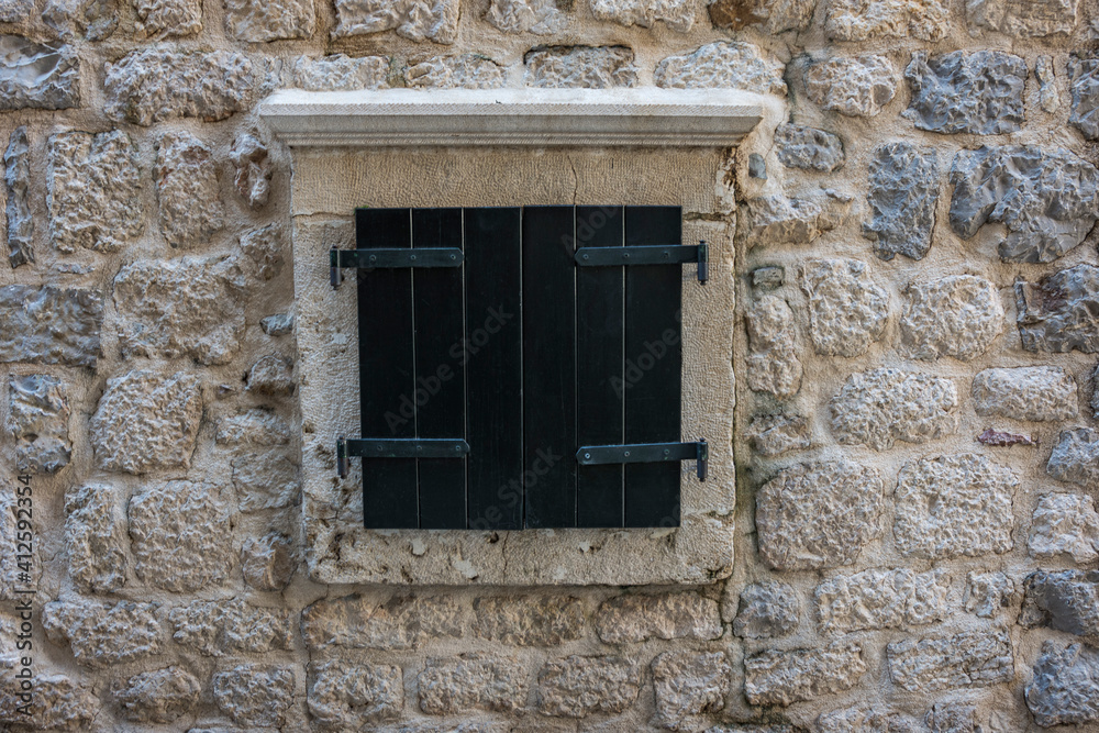 Closed black window shutters in a stonewall surround. Kotor, Montenegro.
