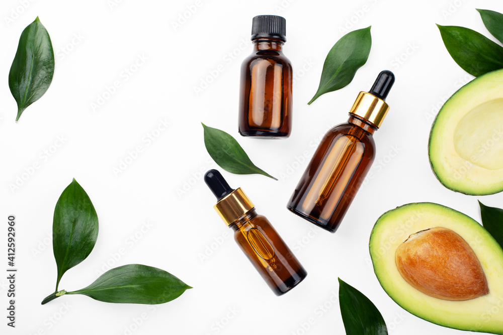 Dropper bottles with fresh ripe avocado and essential oil on white table flat lay Dropper bottles with fresh ripe avocado and essential oil on white table flat lay