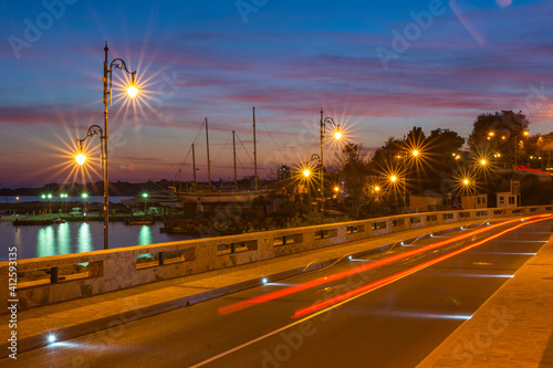 Colorful sunset and light trails motion of the passing by cars. Long exposure view of a harbour, near at the entrance of the UNESCO – protected ancient town of Nessebar, Bulgaria. Tourism concept. © RaDa