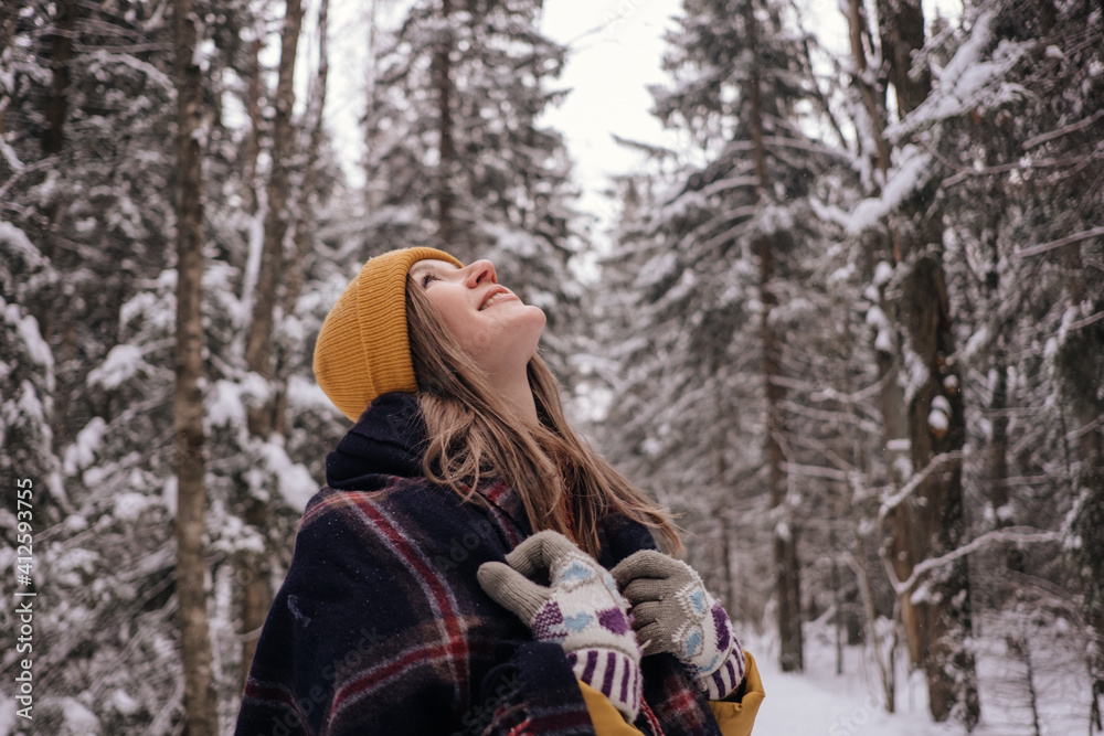 Young Cheerful woman spending time in winter snowy forest. Having fun in winter holidays
