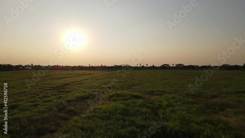 The drone shoots 4K video, top back view. On the grass field that reflected the sunset in the evening