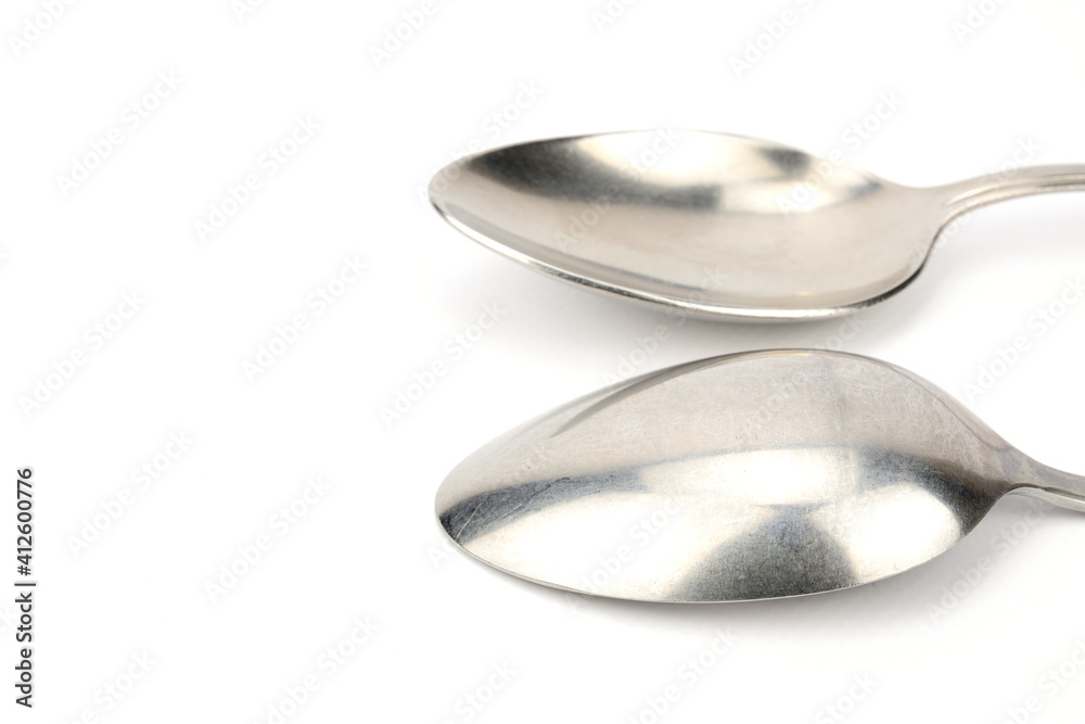 Side view of two tablespoons. One lies with the bottom up, the other down. Side view of two tablespoons. One lies with the bottom up, the other down.