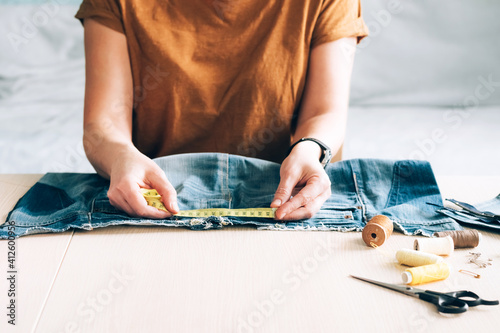 Woman repairs sews reuses fabric from old denim clothes economical reuse