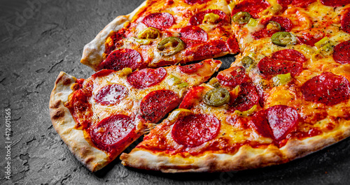 Pepperoni Pizza with Mozzarella cheese, salami, Tomato sauce, pepper, Spices. Italian pizza on Dark grey black slate background photo