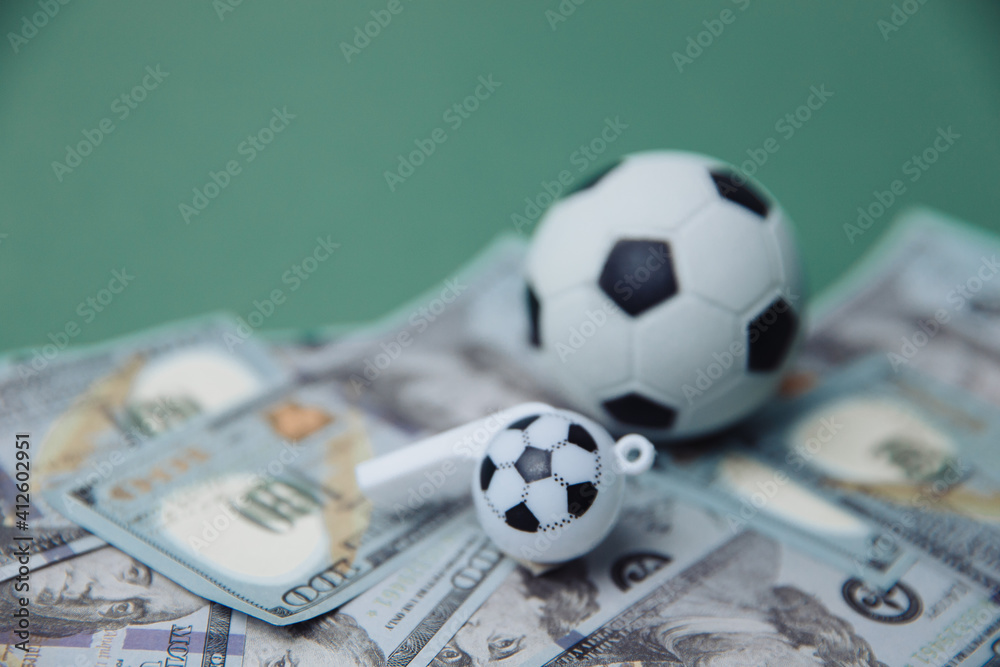 Football Business Concept. Ball and whistle on dollar bills and green background. Soccer gambling money concept. Football Business Concept. Ball and whistle on dollar bills and green background. Soccer gambling money concept.