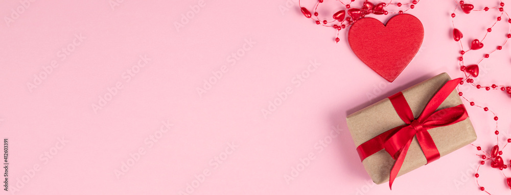 Valentine's day banner. Red heart and gift with red ribbon near beads with hearts on pastel pink colors. Valentine's day concept. Flat lay. - obrazy, fototapety, plakaty 