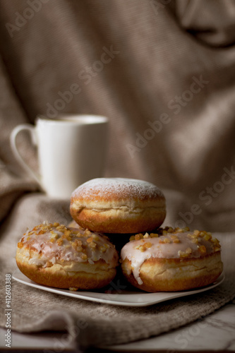Close up on traditional polish donuts, served on Fat Thursday, selective focus, coffee cup at the background