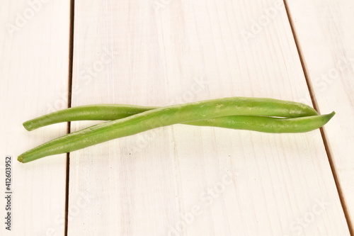 Two pods of bright green, organic, natural, ripe beans, close-up, on a painted wooden table.