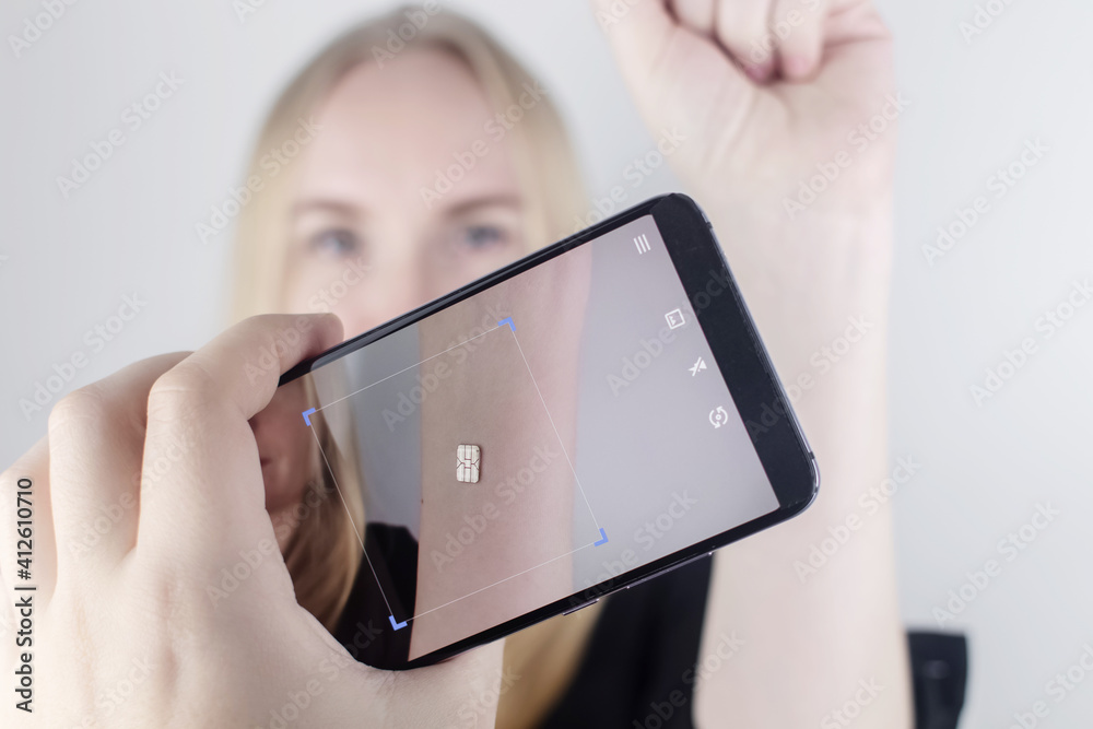 The woman shows his hand with a chip implanted which is read or scanned by a special device
