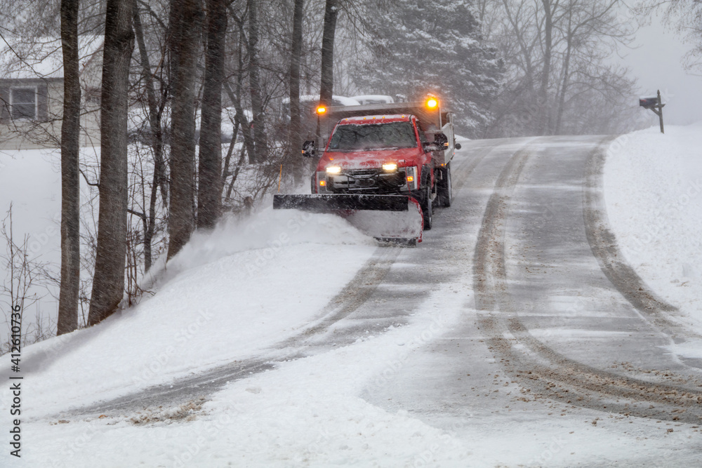 Snowplow in action clearing residential roads during snow storm