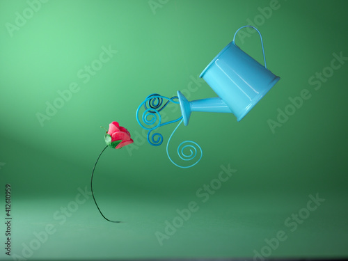 Conceptual flower being watered by a watering can