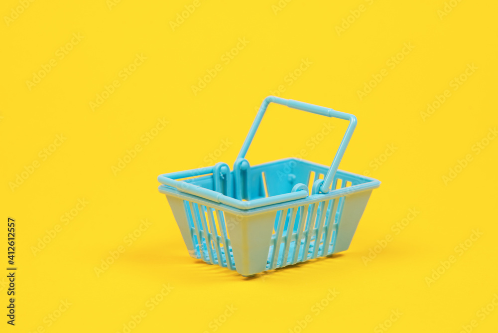 Toy plastic shopping basket on a yellow background with copy space. basket for grocery Toy plastic shopping basket on a yellow background with copy space. basket for grocery