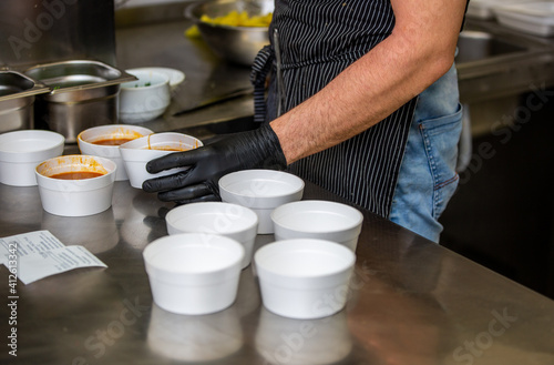 Chef preparing soup to a box in the restaurant for food delivery service to home, online ordering