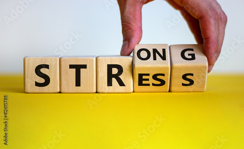 Strong stress symbol. Businessman turns wooden cubes with words 'strong stress'. Beautiful yellow table, white background, copy space. Business and strong stress concept. photo