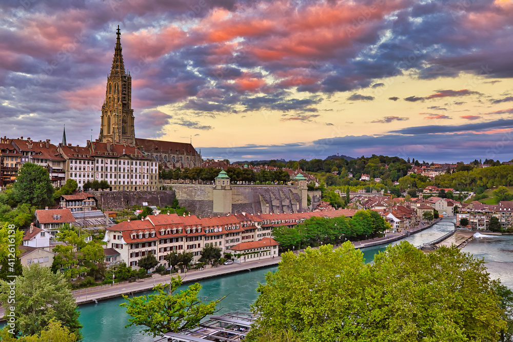 Bern Skyline, capital of Switzerland, and Cathedral, the most important evangelical building of the city at colorful sunset sky. Aerial view of cityscape, UNESCO World Heritage Site, from river Aare.