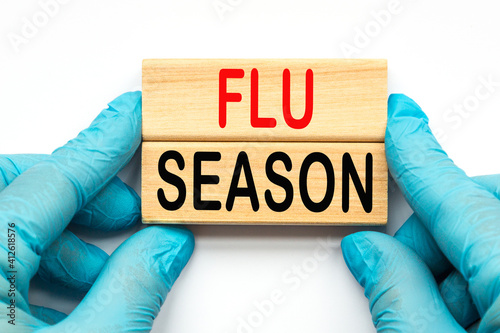 The doctor's hands show the word FLU SEASON . a gloved hand on a white background. Medical concept. the medicine