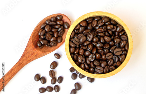 organic brown roasted arabica coffee beans in a wooden bowl and spoon on white background. Focus on coffee beans in a bowl. Famous and good quality coffee bean from Chiangmai, Thailand