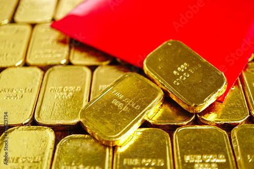 Two gold bars decorate on red envelope (Ang pao) which lay on group of gold bars background.Chinese new year decoration.