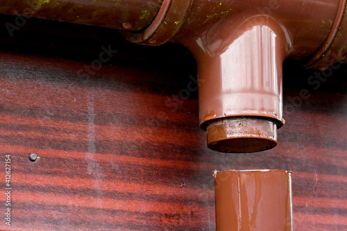 Plastic rain water downpipe detached from the gutter on the roof of a house. No people. photo