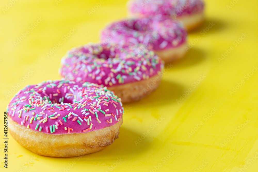 Pink glaze donuts with colorful sprinkles on yellow background. Minimalist concept. Pink glaze donuts with colorful sprinkles on yellow background. Minimalist concept.