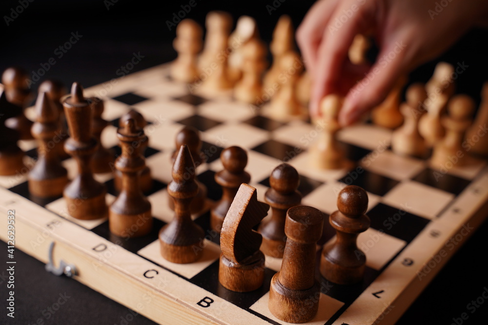 Close up of white and black chess pieces on board. Selective focus on first move of white pawn on chessboard. Concept of intelligent, logical and strategic game. Close up of white and black chess pieces on board. Selective focus on first move of white pawn on chessboard. Concept of intelligent, logical and strategic game.
