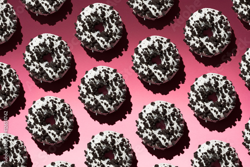 White donuts with black crumb on a pink background