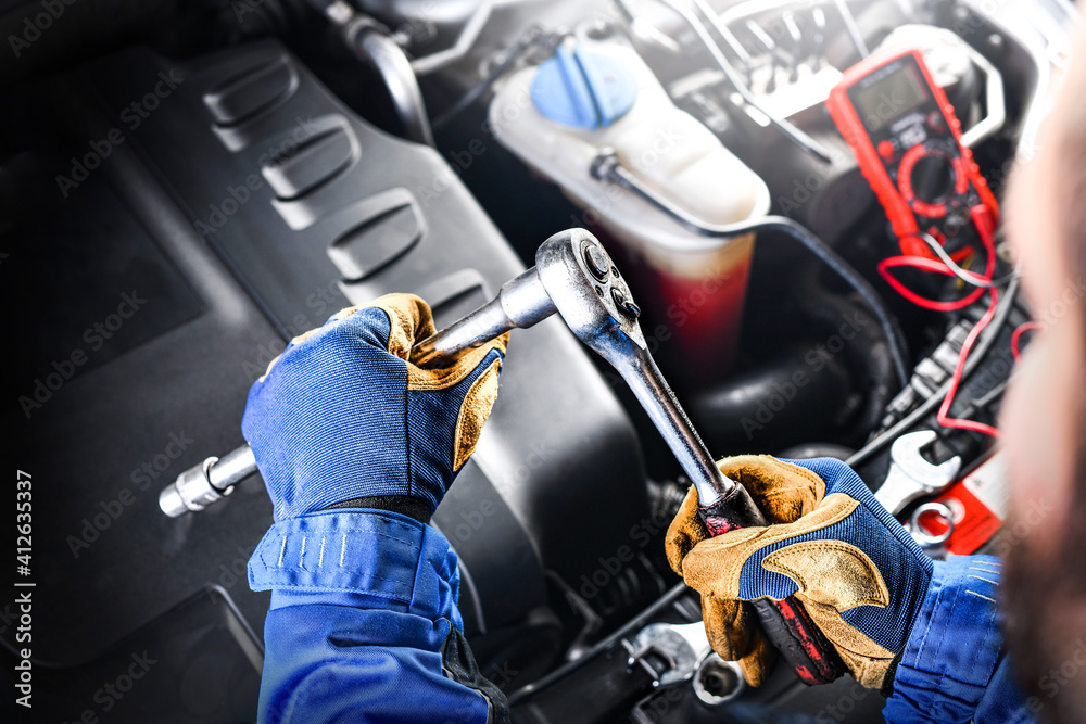 Auto mechanic working on car broken engine in mechanics service or garage.